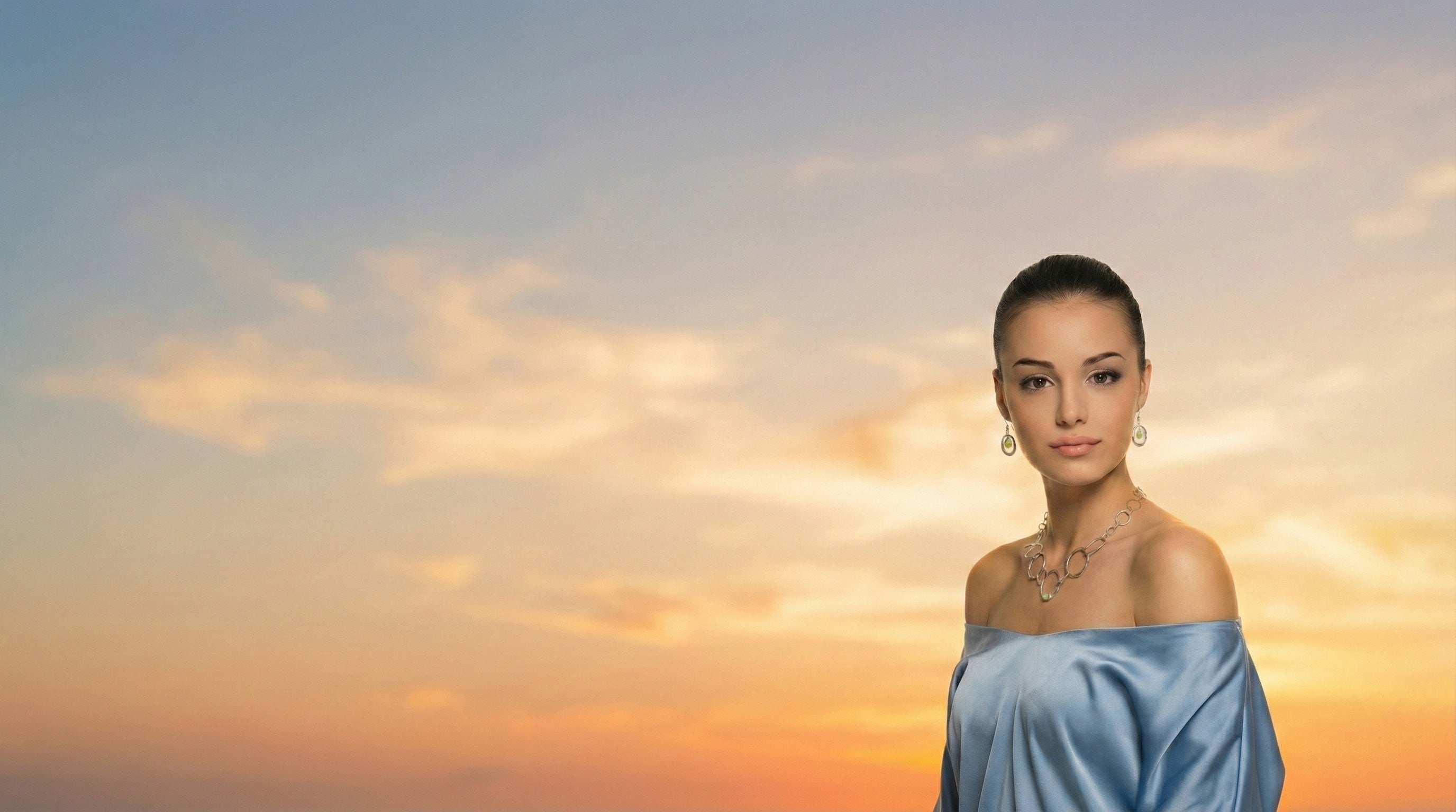 Woman in a light blue dress against a sunset sky
